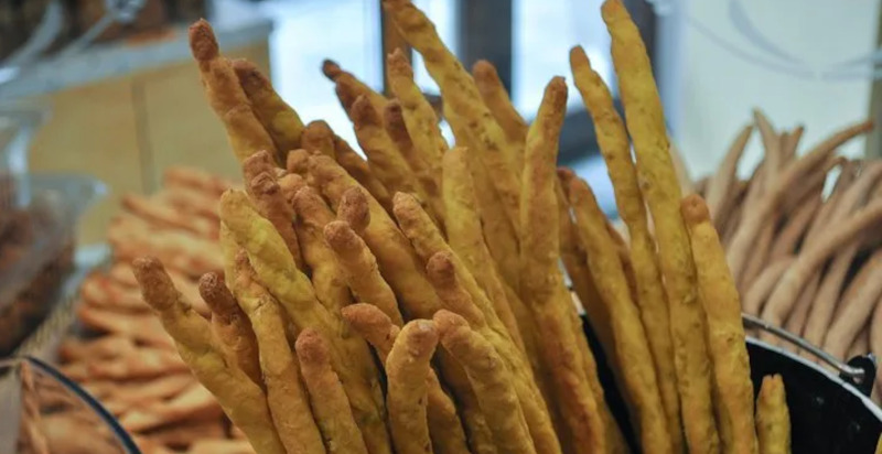 Grissini artigianali serviti con vino piemontese durante un tour street food a Torino