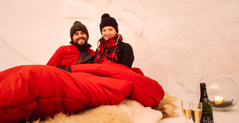 Coppia che brinda con champagne nell'igloo romantico