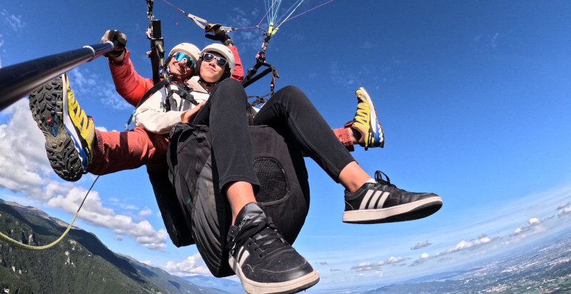 Pilota e passeggero in volo con il parapendio biposto sul Monte Grappa.