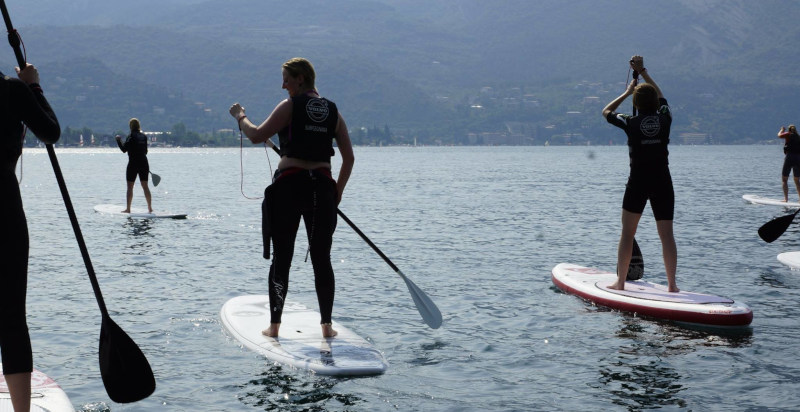 Gruppo di persone che pratica Stand Up Paddle nelle acque limpide del Lago di Garda