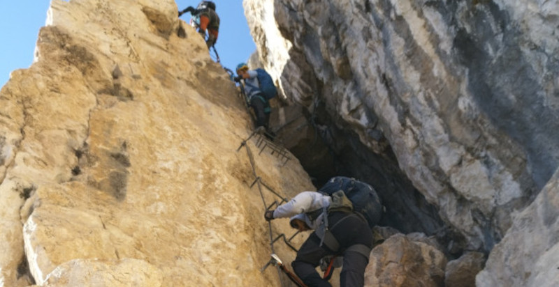 Escursionisti affrontano un passaggio tecnico sulla Via Ferrata Monte Albano