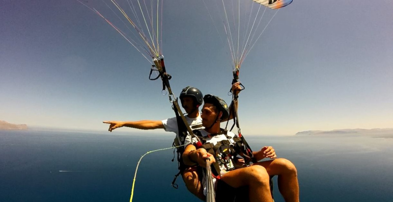 Parapendio biposto in volo sopra il mare cristallino vicino ad Agrigento